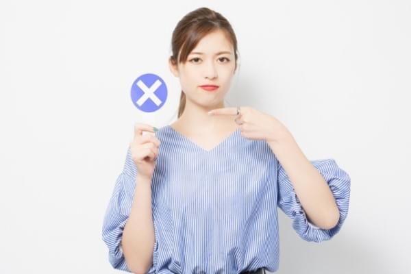 ×のプラカードを掲げる女性のイメージ画像