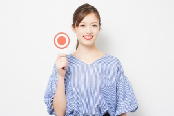 〇のプラカードを掲げる女性のイメージ画像